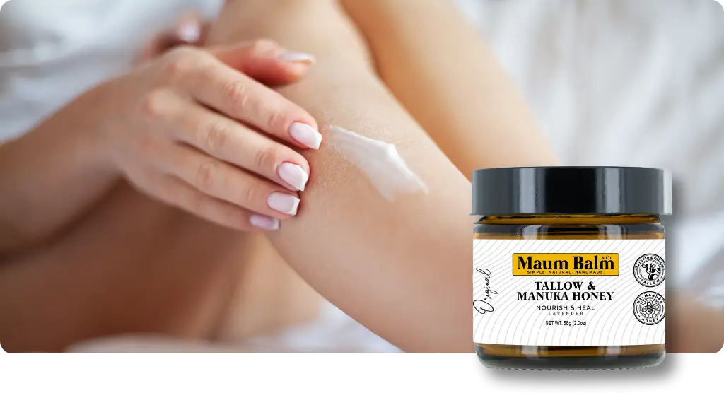 Woman applying Maum Balm Tallow & Manuka Honey to her arm for deep hydration and skin nourishment, with a jar of Maum Balm in the foreground.