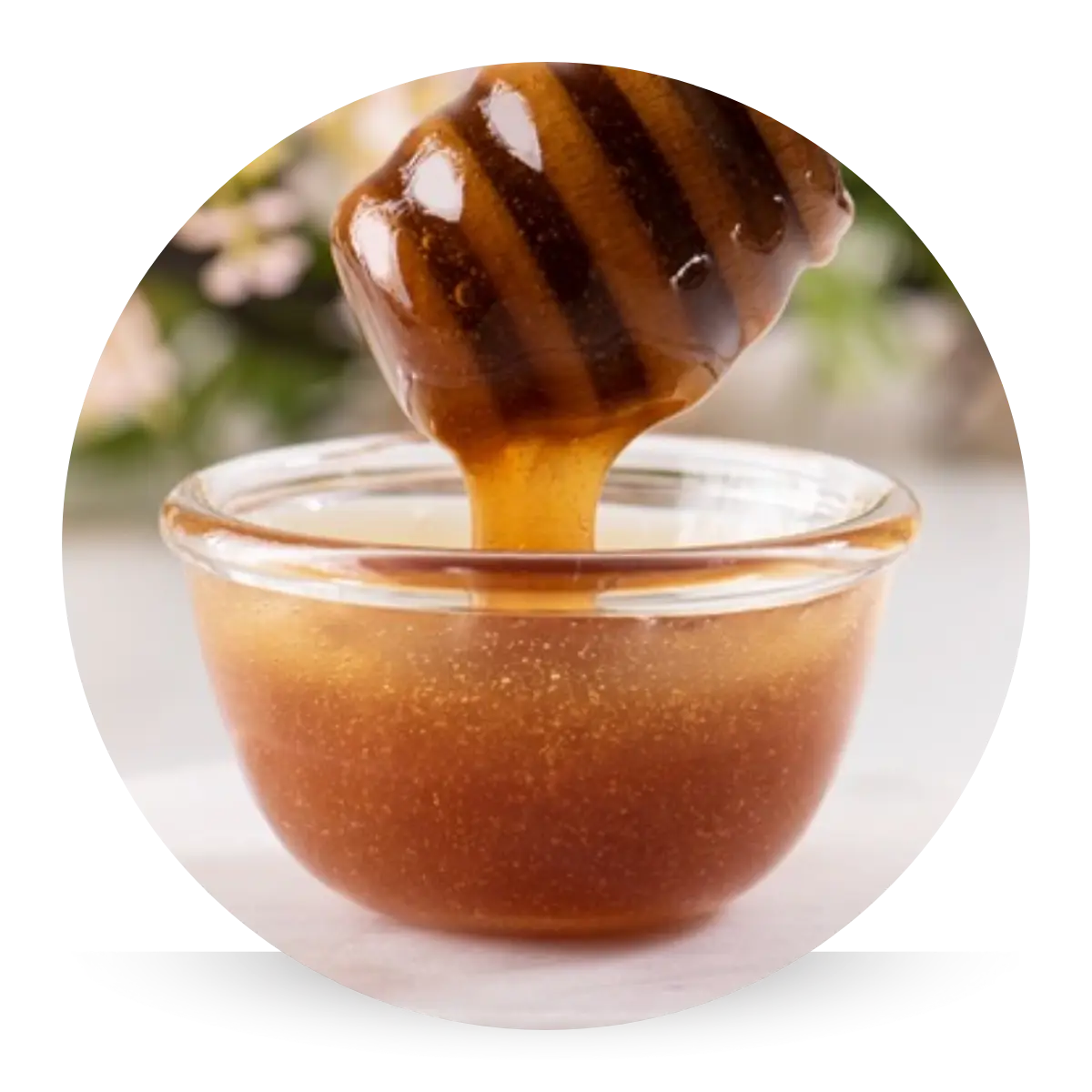 Golden Manuka honey drizzling from a wooden honey dipper, known for locking in moisture, soothing irritation, and supporting sensitive skin.